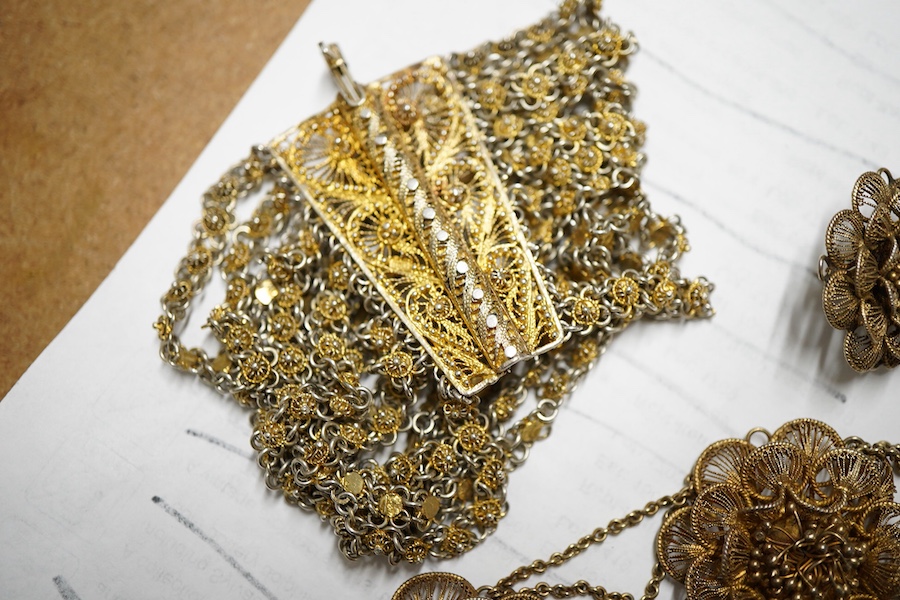 A gilt white metal filigree parure, comprising a necklace, 36cm, with flower head motifs, a pair of flower head earrings and a bracelet.